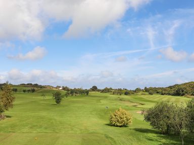 A golf course with a fairway sand bunkers and trees at 19 Parc Delfryn in Benllech