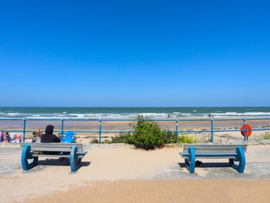 A seaside area with benches facing the beach and ocean at 19 Parc Delfryn in Benllech