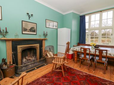 A dining room with a fireplace a wooden table with chairs and a refrigerator at Plas Pontfaen near Fishguard and Newport Pembrokeshire