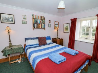 A bedroom with a double bed covered with blue and white striped bedding and two blue towels on a red blanket at Plas Pontfaen near Fishguard and Newport Pembrokeshire