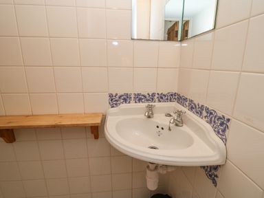 A corner sink with blue patterned tiles and a wooden shelf above at Plas Pontfaen near Fishguard and Newport Pembrokeshire