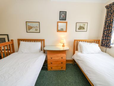 A bedroom with two single beds a wooden bedside table with a lamp and framed pictures on the wall at Plas Pontfaen near Fishguard and Newport Pembrokeshire