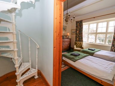 A bedroom with two single beds a dresser armchair and a spiral staircase at Plas Pontfaen near Fishguard and Newport Pembrokeshire