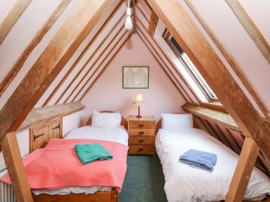 A small attic bedroom with two single beds a wooden chest of drawers and a lamp at Plas Pontfaen near Fishguard and Newport Pembrokeshire