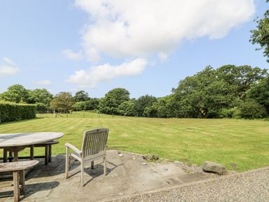 A garden with a table and chair overlooking a grassy area at Plas Pontfaen near Fishguard and Newport, Pembrokeshire