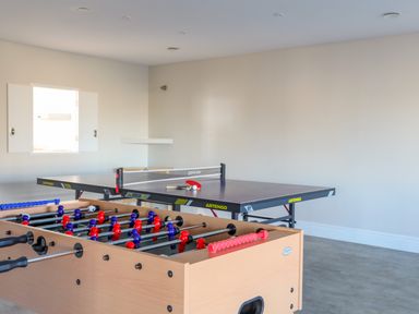 A game room with a foosball table and a ping pong table at Plas Gwylan in Rhosneigr