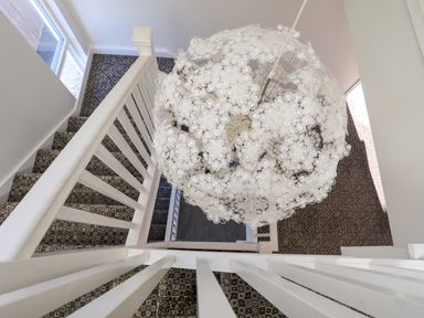 A staircase with patterned carpet and a large spherical pendant light at Plas Gwylan in Rhosneigr