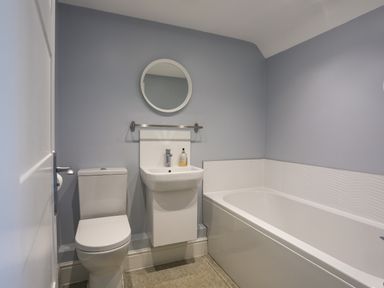 A bathroom with a toilet sink mirror and bathtub at Plas Gwylan in Rhosneigr