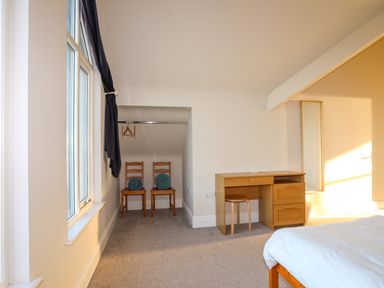A bedroom with two wooden chairs with rolled towels and a wooden desk with a stool at Plas Gwylan in Rhosneigr