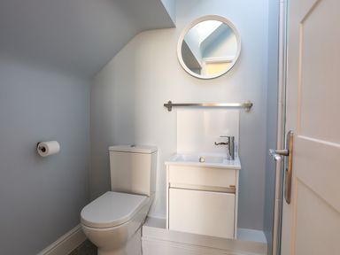 A bathroom with a toilet sink and round mirror at Plas Gwylan in Rhosneigr