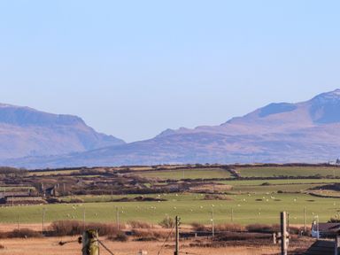 A rural landscape with fields sheep and hills in the background at Plas Gwylan in Rhosneigr
