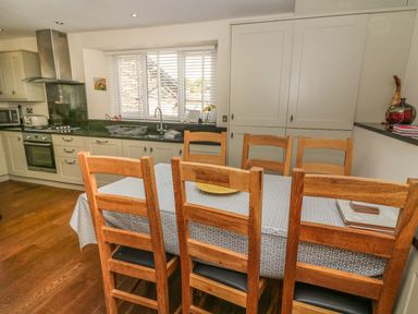 A kitchen with wooden chairs around a table covered with a patterned tablecloth at Woodbine Cottage in Ambleside
