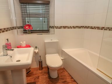 A bathroom with a sink toilet and bathtub with tiled walls and a window with blinds at Woodbine Cottage in Ambleside