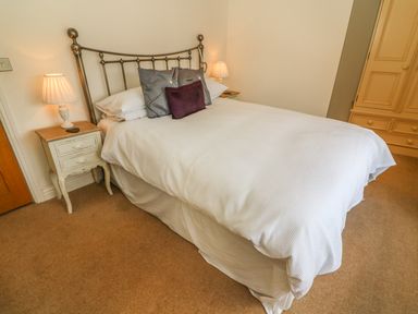 A bedroom with a double bed two bedside tables with lamps and a wardrobe at Woodbine Cottage in Ambleside