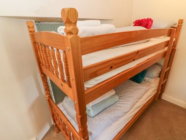 A wooden bunk bed with folded towels and pillows in a small room at Woodbine Cottage Ambleside
