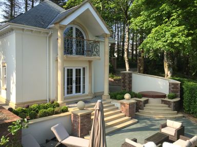 An outdoor patio area with steps leading to a house with columns and a balcony at Hunters Moon in Charlestown