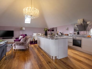An open plan kitchen and living area with wooden floors chandelier and modern kitchen island at Hunters Moon in Charlestown