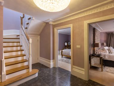 A hallway with wooden stairs and two open doorways showing bedrooms at Hunters Moon in Charlestown