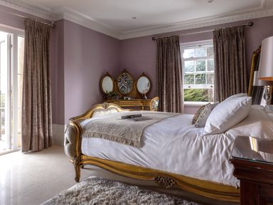 A bedroom with a bed a dressing table with three mirrors curtains on windows at Hunters Moon in Charlestown