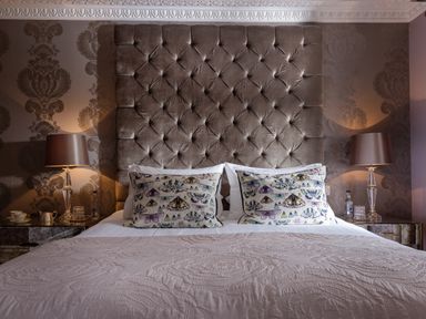 A bedroom with a bed with butterfly patterned pillows and two bedside tables with lamps at Hunters Moon in Charlestown