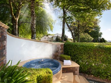 An outdoor hot tub with steam surrounded by stone walls and greenery at Hunters Moon in Charlestown