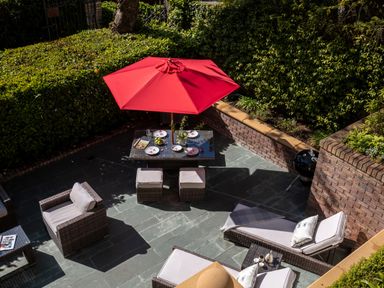 An outdoor patio with wicker furniture a table with a red umbrella and a barbecue grill at Hunters Moon in Charlestown