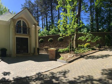 A driveway with a tree and manicured bushes beside a house entrance with double doors and pillars at Hunters Moon in Charlestown