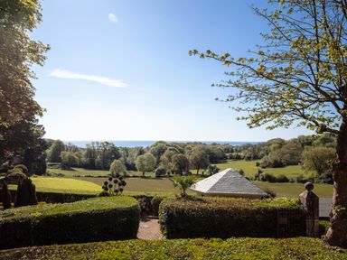 A landscape view of trees fields a small building with a tiled roof and the sea in the distance at Hunters Moon in Charlestown