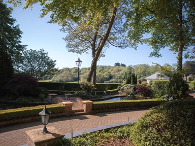 A garden with brick paths a small bridge a fountain and various trees and shrubs at Hunters Moon in Charlestown