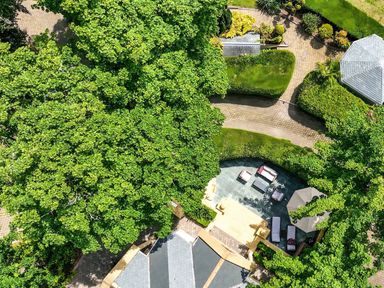 An aerial view of a garden with a paved patio area with outdoor furniture surrounded by trees and shrubs at Hunters Moon in Charlestown