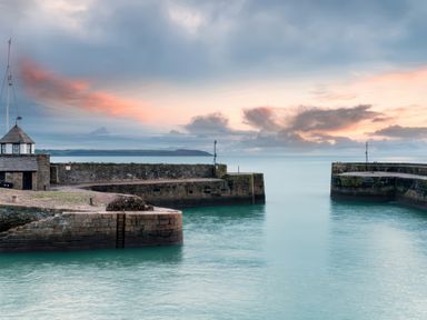 A harbor entrance with stone piers and a small building by the water at Hunters Moon in Charlestown