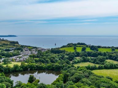 A coastal village by the sea with green fields trees and a small pond at Hunters Moon in Charlestown