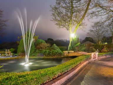 A garden with a water fountain pond a brick bridge and a lamp post at Hunters Moon in Charlestown