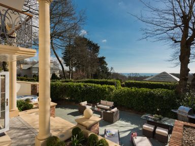 An outdoor patio area with seating arrangements a barbecue grill and surrounding greenery at Hunters Moon in Charlestown