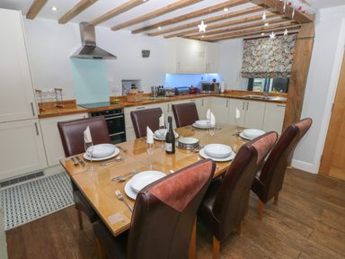 A dining table set for six in a kitchen with white cabinets and wooden countertops at Blacksmiths Cottage in Pembroke