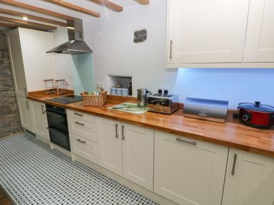 A kitchen with white cabinets wooden countertops and appliances at Blacksmiths Cottage in Pembroke