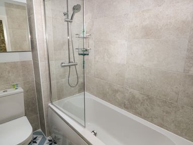 A bathroom with a bathtub shower combination and toilet at Blacksmiths Cottage in Pembroke