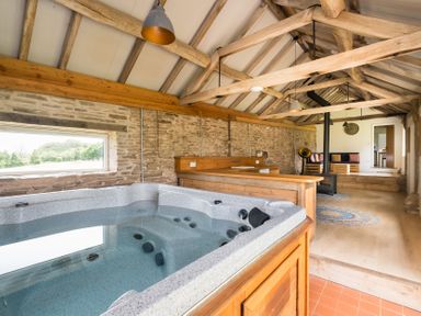 A room with a hot tub, wooden counter, fireplace, and seating at Henhouse Farm in Bodenham