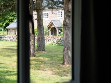 A view of a house and trees from a window at Henhouse Farm Bodenham