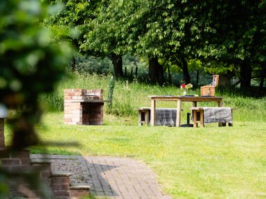 A garden with a barbecue grill and a table set with flowers at Henhouse Farm in Bodenham