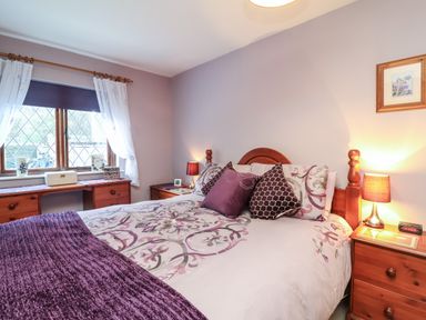 A bedroom with a wooden bed and side tables with lamps at Old Farm Cottage in Woolacombe