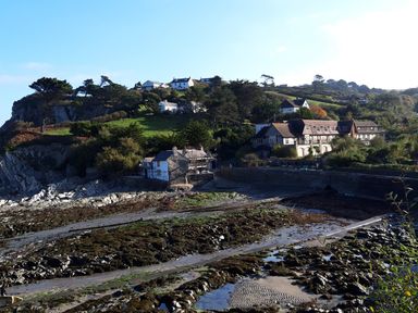 A coastal village with houses on a hillside and rocky shore at Old Farm Cottage in Woolacombe