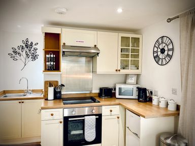 A kitchen with stove oven microwave toaster kettle and canisters at The Studio in Crackington Haven