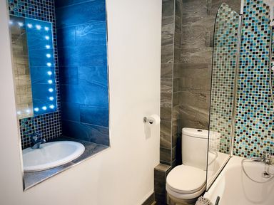 A bathroom with a sink, toilet, and bathtub with mosaic tiles at The Studio in Crackington Haven