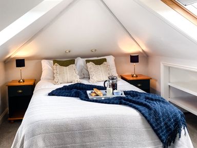 A bedroom with a bed two bedside tables with lamps and a breakfast tray at Penkenna in Crackington Haven