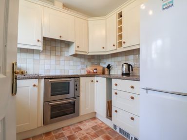 A kitchen with white cabinets a double oven a kettle on the counter and a white refrigerator at Bay Tree Cottage in Peasenhall