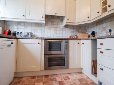 A kitchen with cream cabinets countertop appliances and an oven at Bay Tree Cottage in Peasenhall