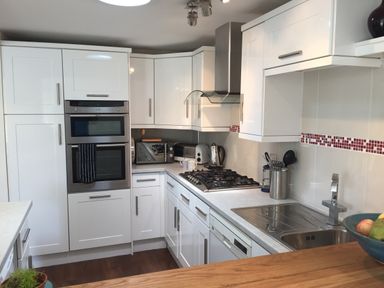 A kitchen with white cabinets gas stove double oven microwave toaster kettle and sink at Maceley in Kingsbridge