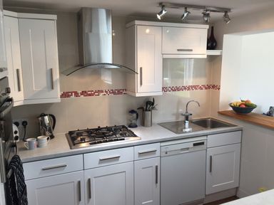 A kitchen with white cabinets a gas stove a stainless steel sink and a fruit bowl on the counter at Maceley in Kingsbridge