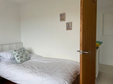 A small bedroom with a single bed white bedding and a pillow with house patterns at Maceley in Kingsbridge